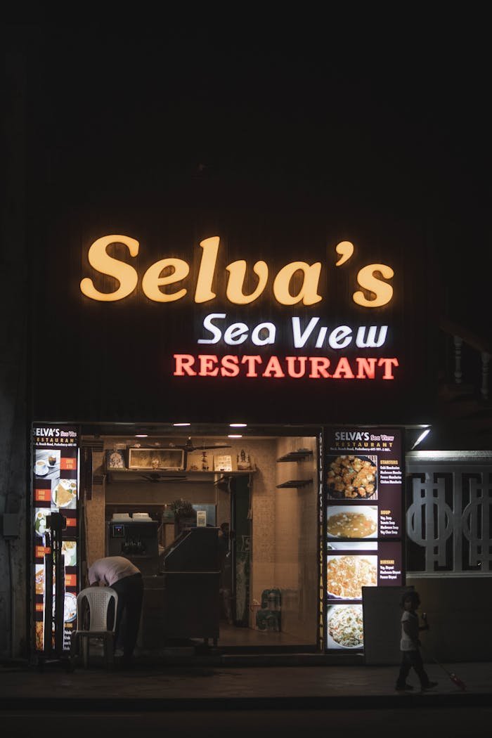 Front view of Selvas Sea View Restaurant illuminated at night in Puducherry, India, capturing local dining atmosphere.